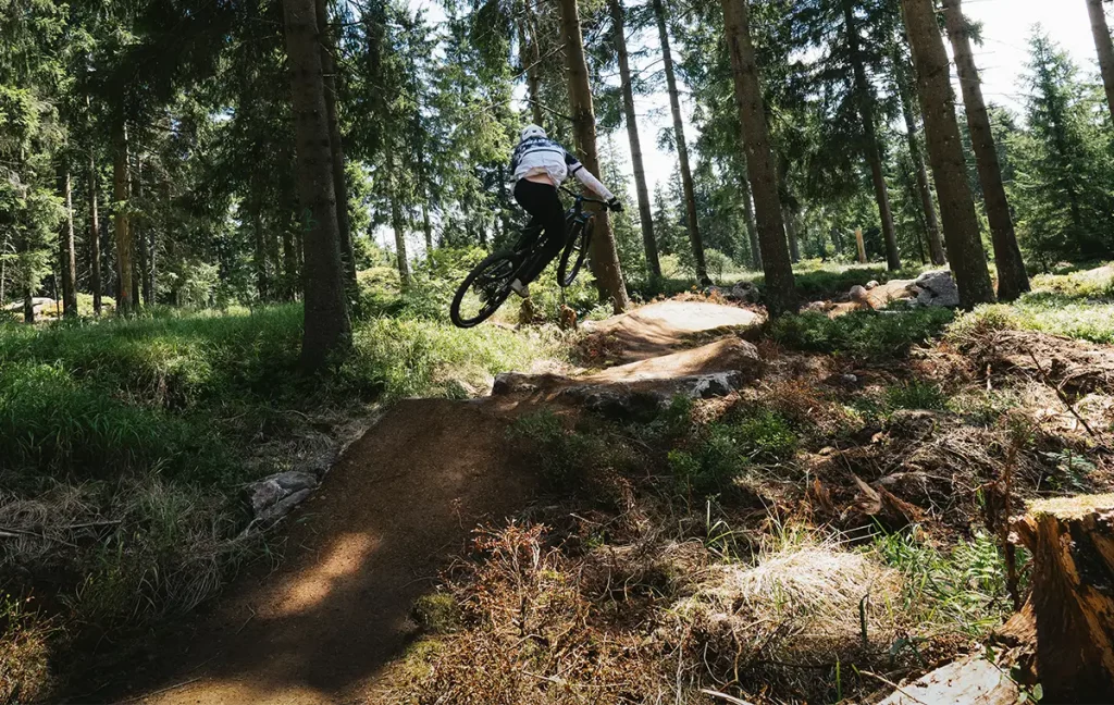 Mountainbiker springt mit angehobenem Vorderrad über eine felsige Passage des fOXtrott.